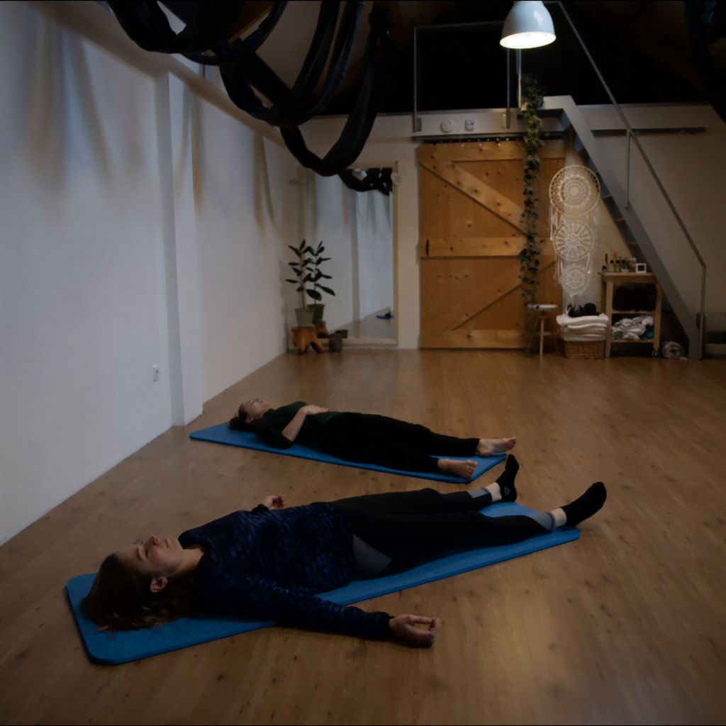 Twee personen liggen op yogamatjes